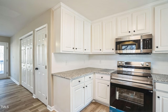 kitchen featuring white cabinets, appliances with stainless steel finishes, light wood-type flooring, and light stone countertops