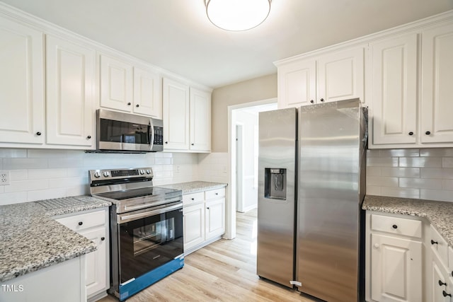 kitchen with light stone counters, white cabinets, and stainless steel appliances