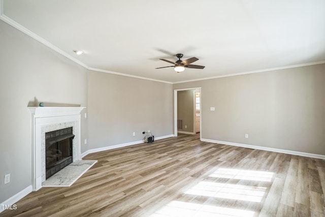 unfurnished living room featuring a fireplace, light wood-type flooring, ceiling fan, and ornamental molding