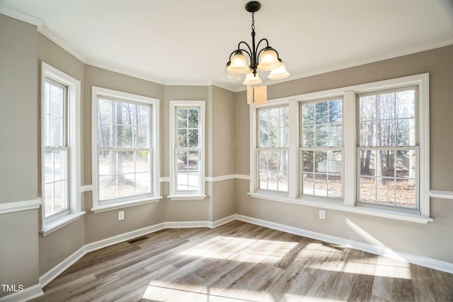 unfurnished dining area with light wood-type flooring, crown molding, and a chandelier