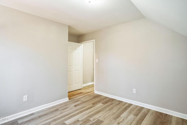 empty room with vaulted ceiling and light hardwood / wood-style flooring