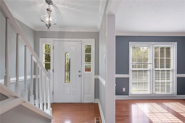 entrance foyer featuring hardwood / wood-style flooring, crown molding, and a chandelier