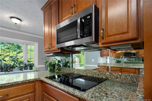 kitchen featuring a textured ceiling, black electric cooktop, light stone counters, and crown molding