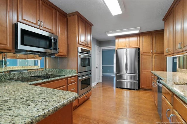 kitchen featuring appliances with stainless steel finishes, light hardwood / wood-style flooring, and light stone counters