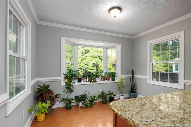 interior space with a textured ceiling, hardwood / wood-style flooring, and crown molding