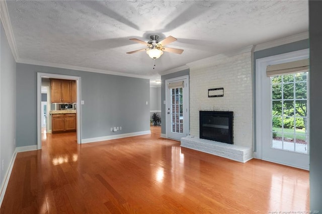 unfurnished living room with crown molding, a fireplace, ceiling fan, and a textured ceiling