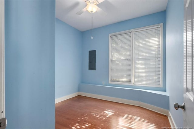 empty room with electric panel, hardwood / wood-style flooring, and ceiling fan