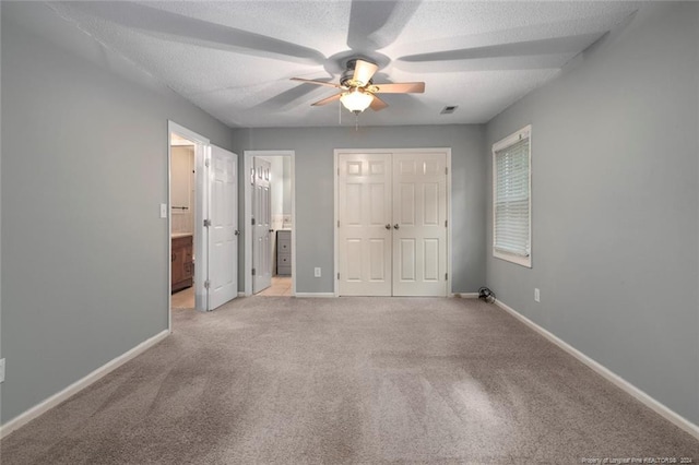 unfurnished bedroom with connected bathroom, ceiling fan, light colored carpet, and a textured ceiling