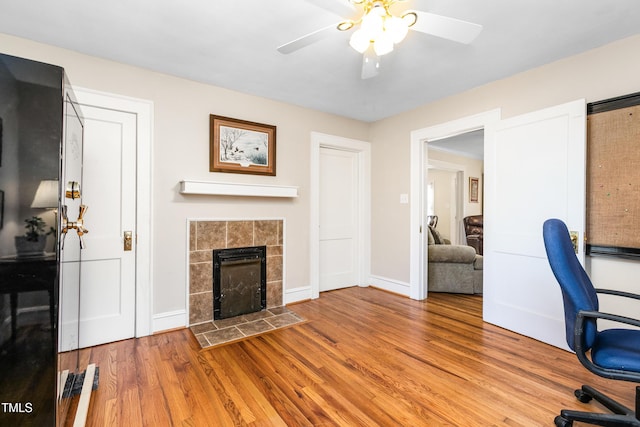 office space featuring ceiling fan, light hardwood / wood-style floors, and a tile fireplace