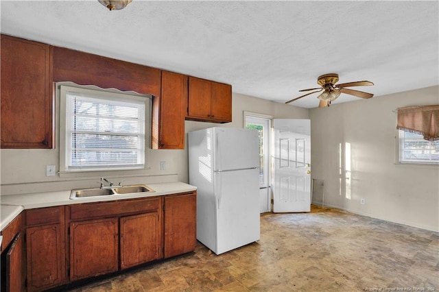 kitchen with a textured ceiling, white refrigerator, ceiling fan, and sink