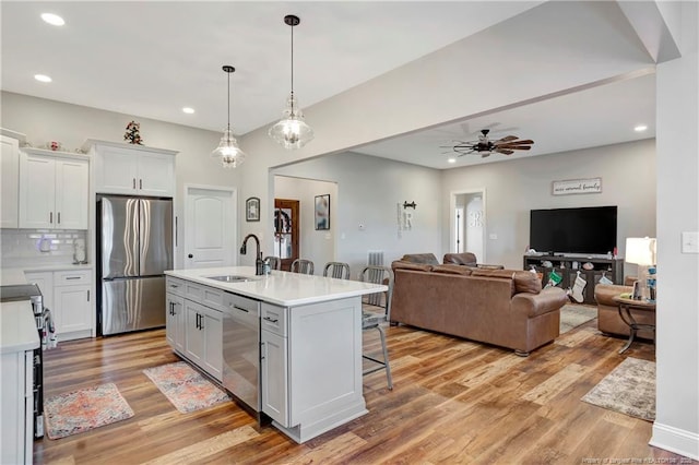 kitchen featuring light wood-style flooring, stainless steel appliances, a breakfast bar, a sink, and decorative backsplash