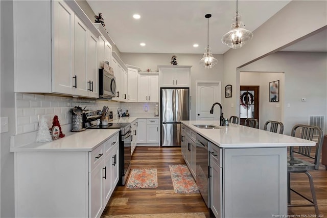 kitchen with a breakfast bar area, dark wood-style flooring, a sink, light countertops, and appliances with stainless steel finishes