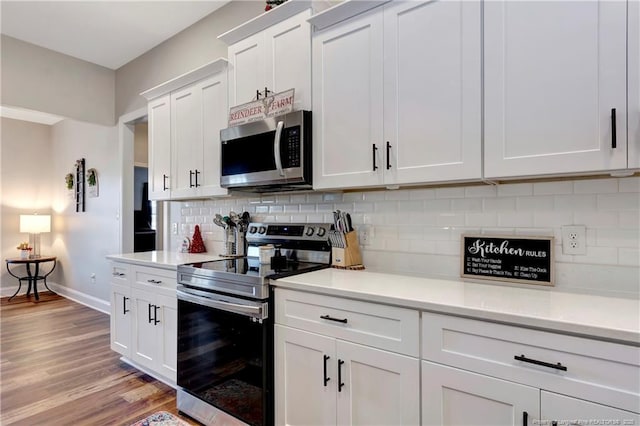 kitchen featuring stainless steel appliances, tasteful backsplash, light countertops, white cabinetry, and light wood-type flooring