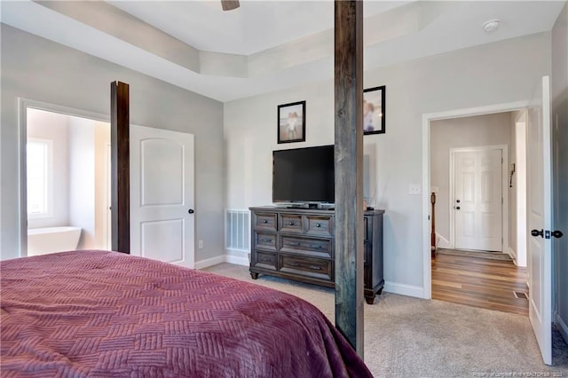 bedroom featuring a ceiling fan, visible vents, baseboards, a tray ceiling, and carpet