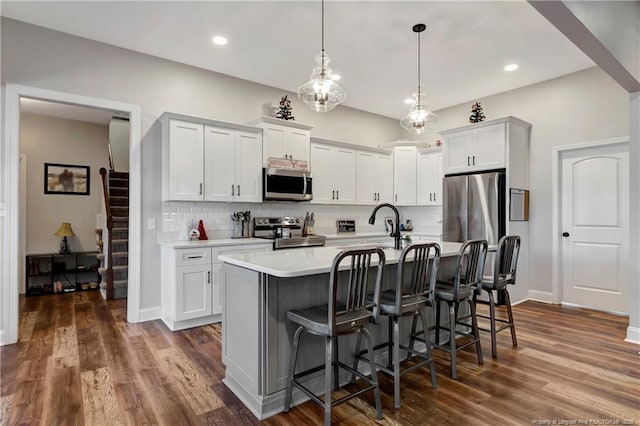 kitchen featuring a breakfast bar, dark wood-style floors, appliances with stainless steel finishes, and light countertops