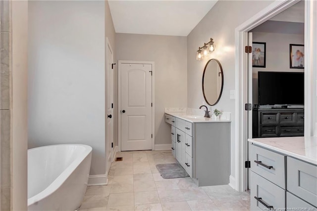 bathroom featuring a freestanding tub, vanity, and baseboards