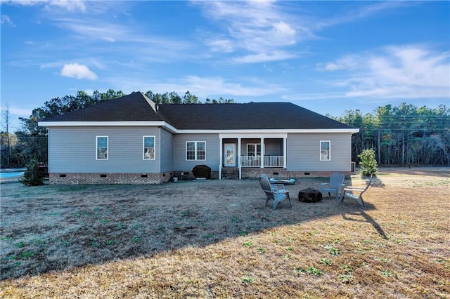 rear view of property featuring a yard, an outdoor fire pit, and crawl space