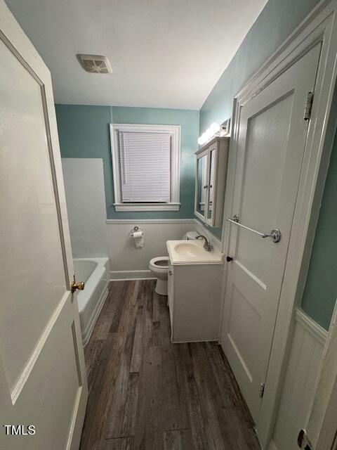 bathroom featuring hardwood / wood-style floors, vanity, a tub to relax in, and toilet