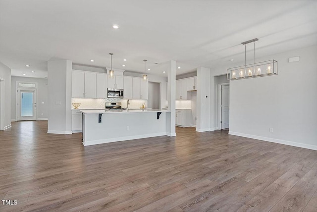 kitchen with stainless steel appliances, white cabinetry, decorative light fixtures, and a spacious island