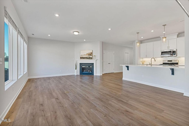 unfurnished living room with light hardwood / wood-style flooring and sink