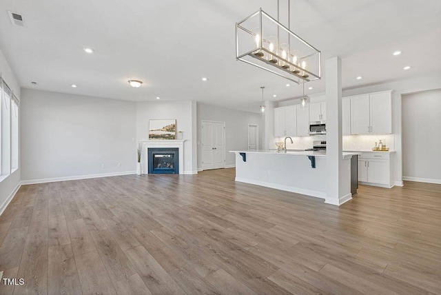 unfurnished living room featuring sink and light hardwood / wood-style flooring