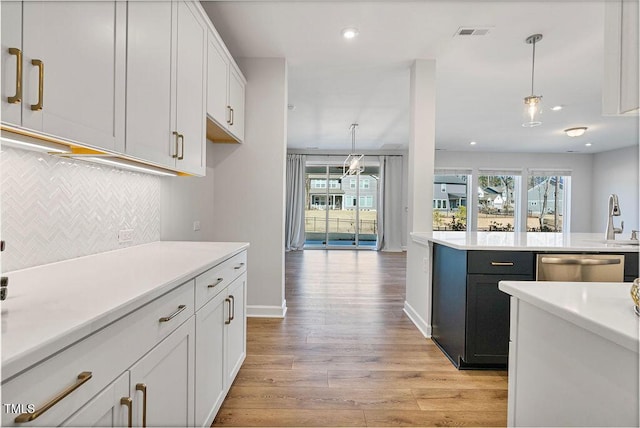 kitchen with white cabinetry, light hardwood / wood-style flooring, stainless steel dishwasher, backsplash, and hanging light fixtures