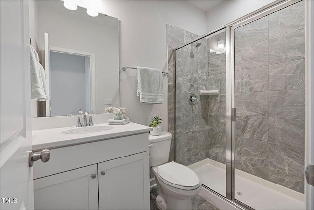 bathroom featuring toilet, a shower with shower door, and vanity