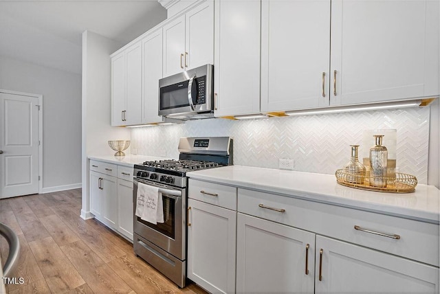 kitchen featuring stainless steel appliances, white cabinets, decorative backsplash, and light hardwood / wood-style floors