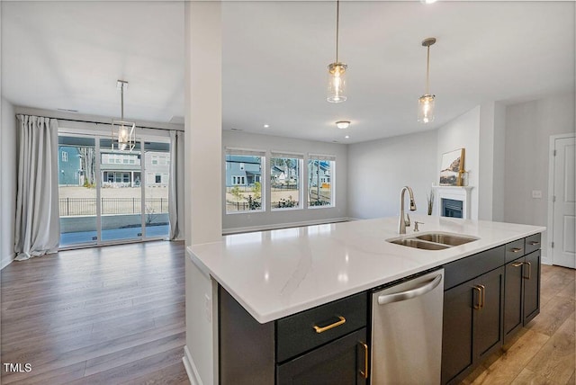 kitchen with stainless steel dishwasher, a center island with sink, sink, and light hardwood / wood-style floors