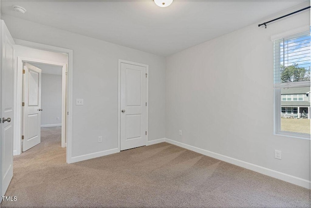 unfurnished bedroom with a closet and light colored carpet