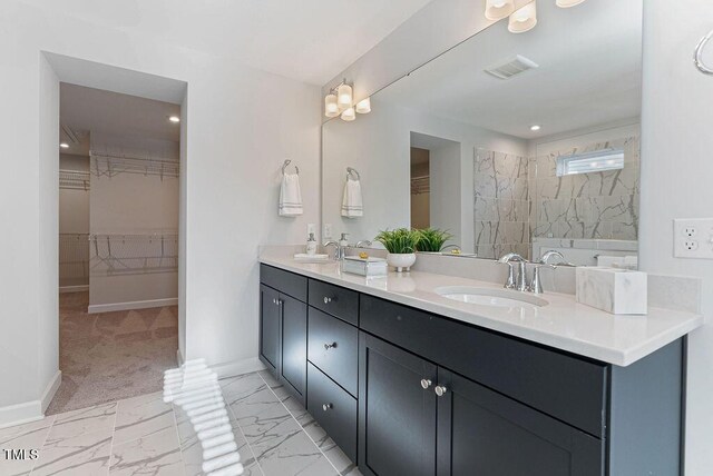 bathroom with a tile shower and vanity