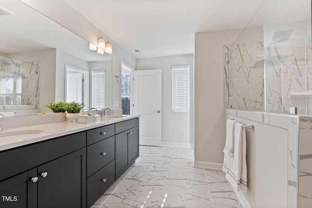 bathroom with a wealth of natural light, a tile shower, and vanity