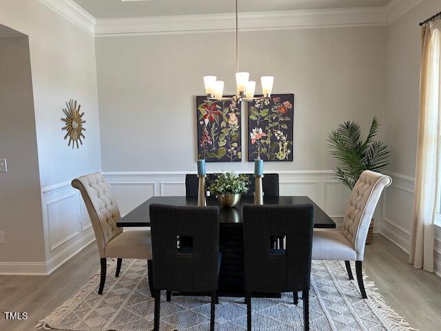 dining room with a notable chandelier, wood-type flooring, and crown molding