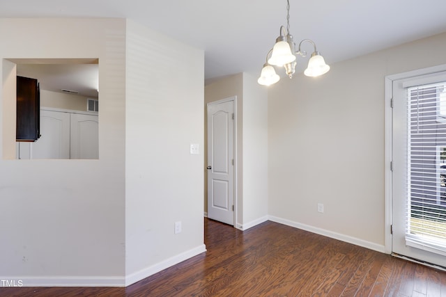 spare room featuring dark hardwood / wood-style floors, a wealth of natural light, and a notable chandelier