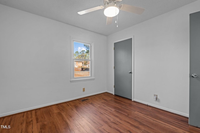 empty room with ceiling fan and dark hardwood / wood-style flooring