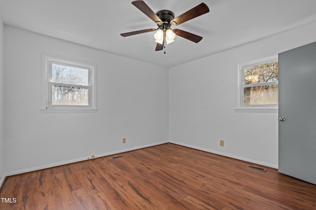 unfurnished room with a wealth of natural light, ceiling fan, and dark wood-type flooring