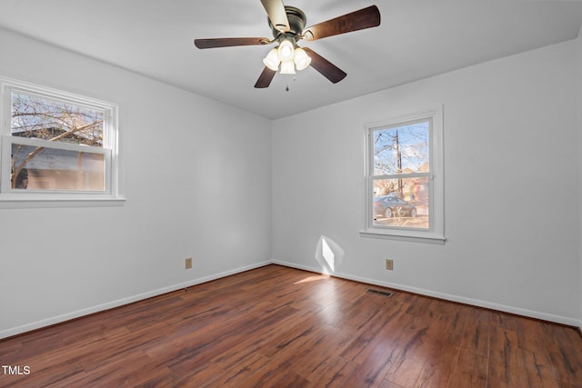 spare room featuring plenty of natural light, ceiling fan, and dark hardwood / wood-style flooring