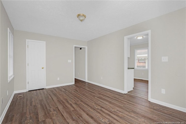 unfurnished bedroom featuring a textured ceiling and dark hardwood / wood-style floors