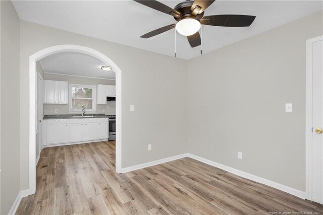 empty room featuring light wood-type flooring, ceiling fan, and sink