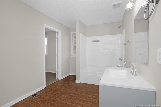 bathroom featuring wood-type flooring, vanity, shower / bath combination, and a textured ceiling