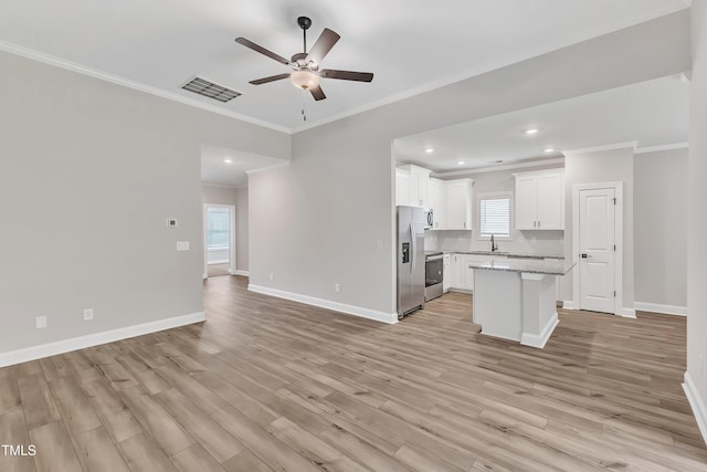 interior space with white cabinetry, a center island, ceiling fan, light stone countertops, and sink