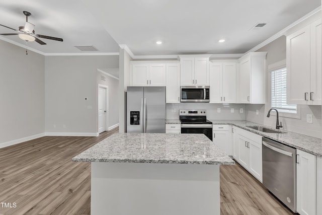 kitchen featuring white cabinets, stainless steel appliances, a kitchen island, and sink