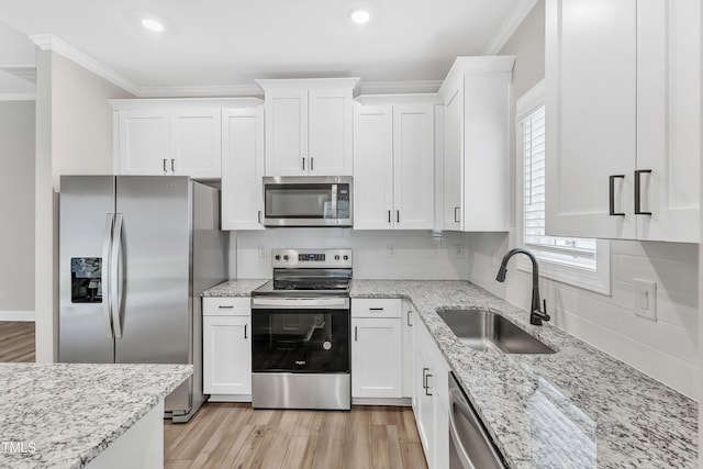 kitchen featuring white cabinets, appliances with stainless steel finishes, ornamental molding, and sink