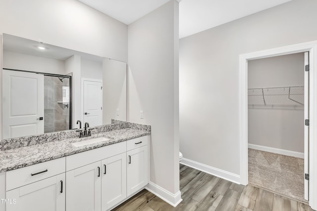 bathroom featuring hardwood / wood-style floors, vanity, toilet, and an enclosed shower