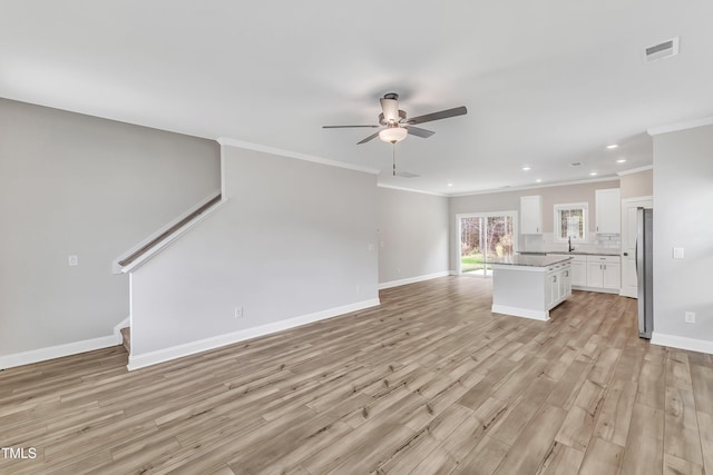 unfurnished living room with ceiling fan, light hardwood / wood-style flooring, crown molding, and sink