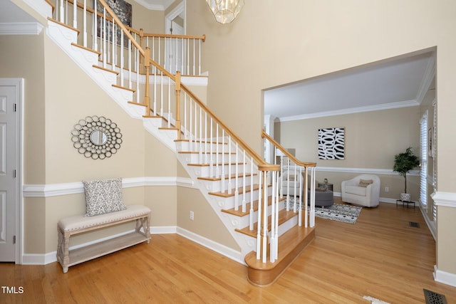 staircase featuring wood-type flooring and ornamental molding