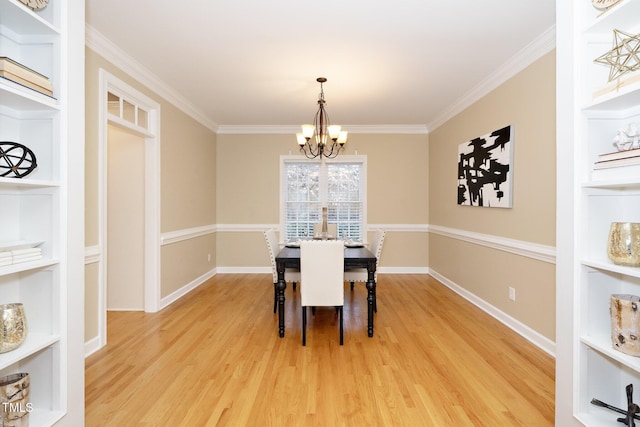 dining space with built in shelves, light hardwood / wood-style floors, ornamental molding, and a chandelier