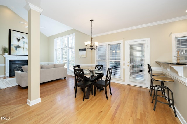 dining room featuring decorative columns, vaulted ceiling, ornamental molding, light hardwood / wood-style floors, and a chandelier