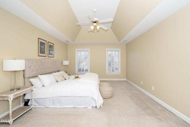 carpeted bedroom featuring ceiling fan and a tray ceiling