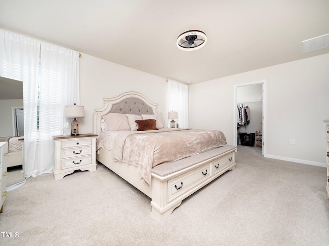 bedroom with a spacious closet, a closet, and light colored carpet